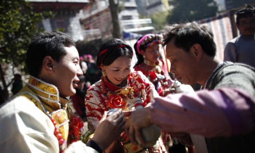 Erja, center, and Baima, left, celebrate with guests during their traditional Tibetan wedding near Danba, Sichuan Province Jan. 26, 2012. China has turned to promoting interracial marriage in an apparent attempt to assimilate Tibetans and stamp out rebellious impulses. (Photo courtesy: Carlos Barria / Reuters/REUTERS)