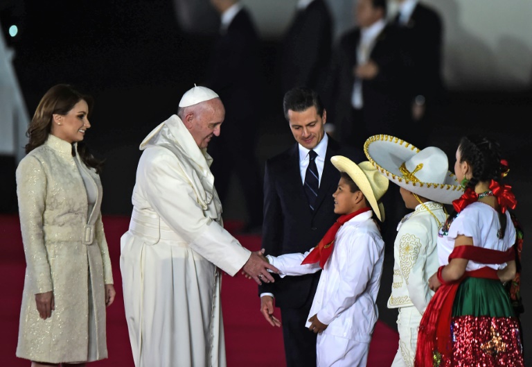 Pope Francis (C) greets Mexican children next to Mexican President Enrique Pena Nieto (R) next to First Lady Angelica Rivera (L) upon his arrival at Benito Juarez international airport in Mexico City on February 12, 2016. (Photo courtesy: AFP)